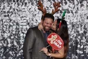 Couple in antlers kissing with Christmas prop