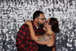 Couple kissing in front of silver backdrop