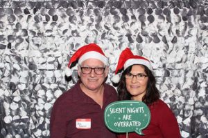 Couple in Santa hats holding funny Christmas sign