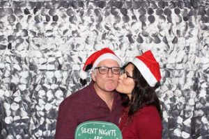 Woman kissing man wearing Santa hats