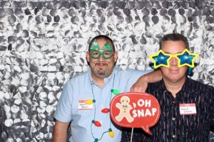 Two men in photo booth with festive glasses