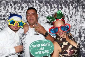 Three people wearing oversized holiday props, holding drinks