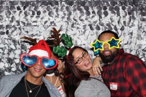 Friends in photo booth wearing holiday props