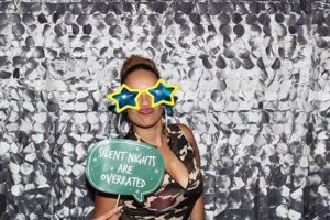 Person wearing star-shaped glasses holding 'Silent Nights' sign