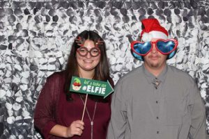 Two people wearing Santa hat and holiday props