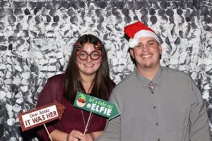 Two people smiling with Christmas photo booth props