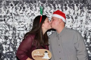 Couple kissing in photo booth wearing Christmas props