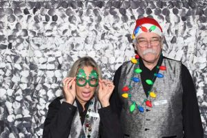 Two people wearing Christmas accessories in photo booth