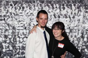 Two smiling people with silver sequin backdrop