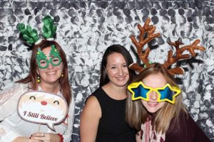 Three friends with holiday antlers and novelty glasses