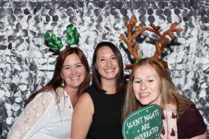 Three women wearing festive reindeer antlers smiling