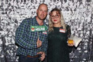 Two people posing with elf sign and drink