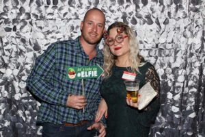 Couple posing at festive photo booth with props