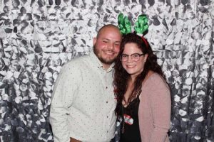 Smiling couple posing with green reindeer antlers