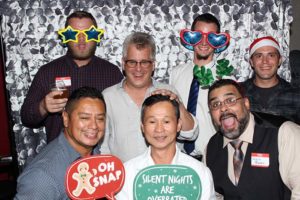 Seven men posing with festive photo props