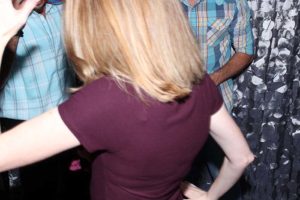 Back view of blonde woman at crowded party
