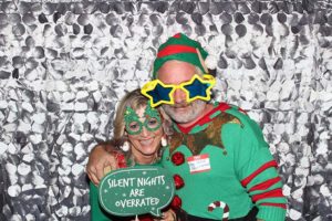 Couple in Christmas costumes holding humorous sign