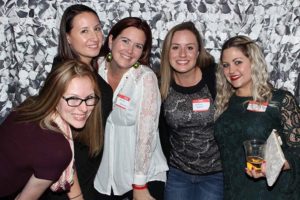Group of five women smiling at social event