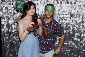 Two people posing with holiday props, silver backdrop