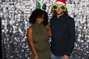 Two people wearing holiday props, silver backdrop