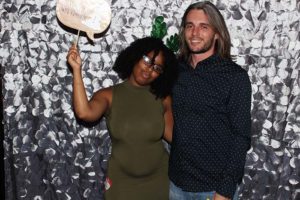 Two people posing with prop against silver backdrop