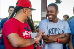 Two men laughing and talking at outdoor party
