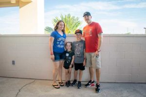 Smiling family of four standing by wall