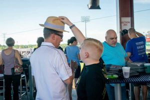Boy placing straw hat on man's head