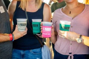 People holding colorful plastic cups at event
