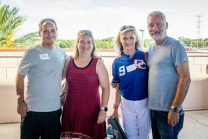 Four adults smiling outdoors at casual gathering