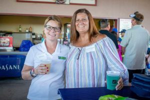 Two smiling women holding drinks at event