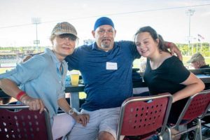 Three people smiling at baseball stadium seats