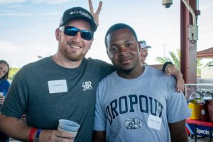 Two men smiling with arm around at event