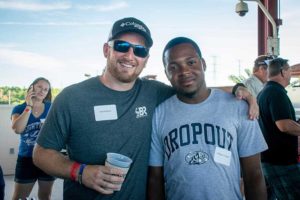 Two men smiling together at outdoor event