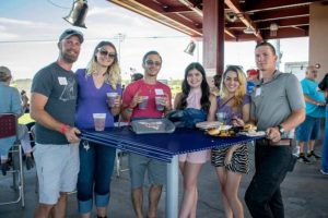 Six smiling friends at outdoor event table