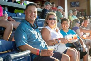 Smiling family holding drinks at baseball game