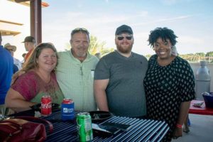 Four adults smiling at outdoor picnic table