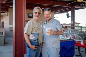 Two men smiling at outdoor event with drink