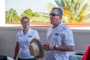 Two volunteers in white shirts near recycling bin
