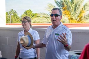Man animatedly speaking beside woman holding hat
