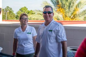 Two smiling people wearing white polo shirts