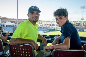Man and teenage boy smiling at baseball stadium